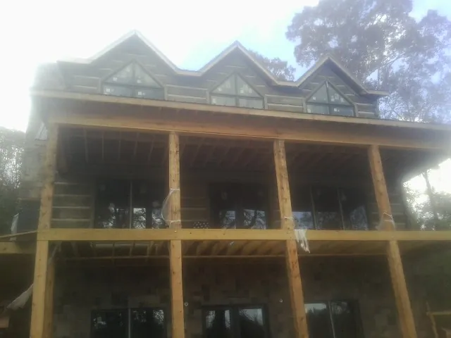 Dormers and porch framing on a large log home under construction — Roof Coating work by our crew in Sturgis