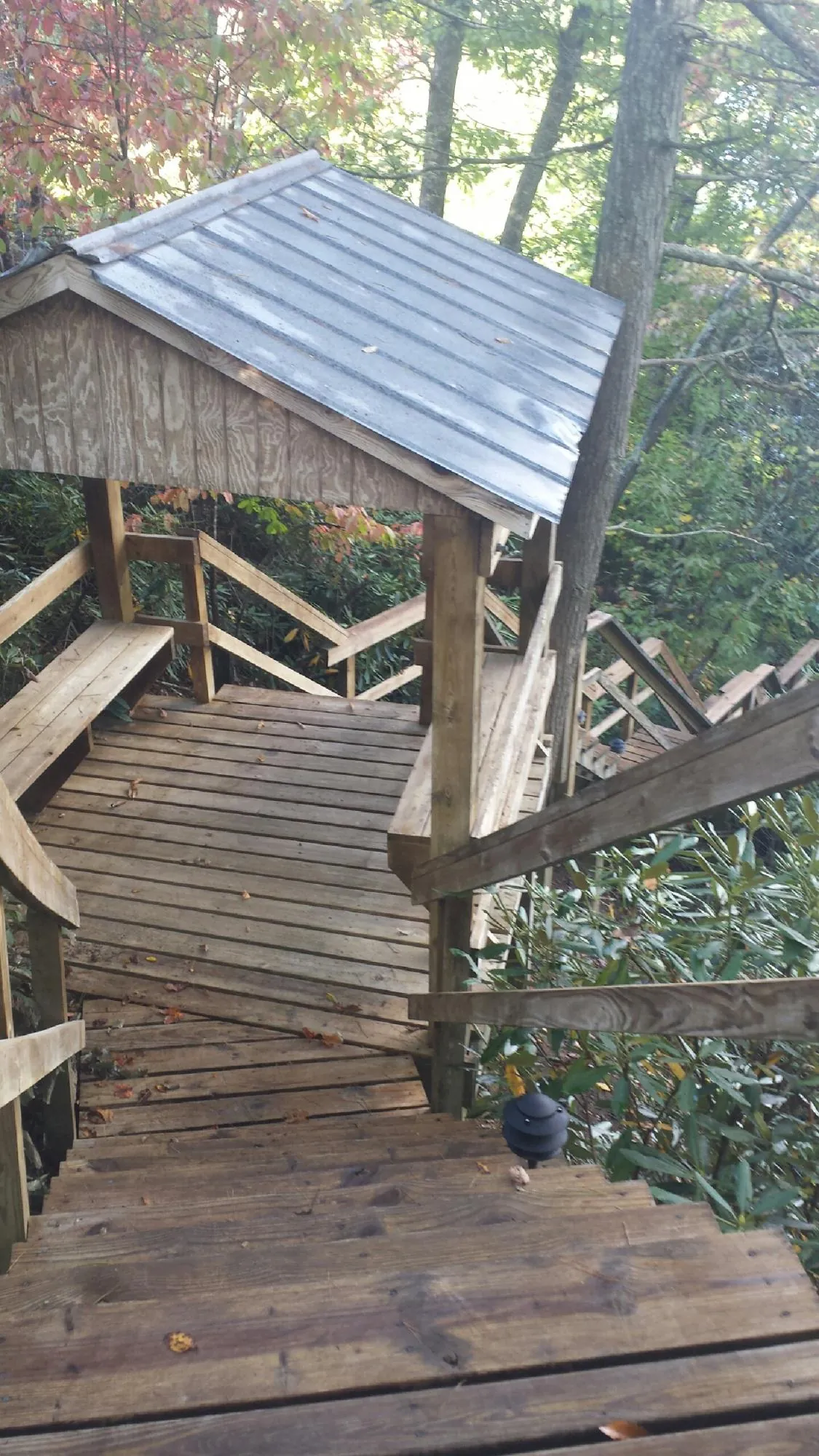 Metal roofed shelter over wooden steps on a wooded walkway — Skylight Repair & Installation work by our crew in Sturgis
